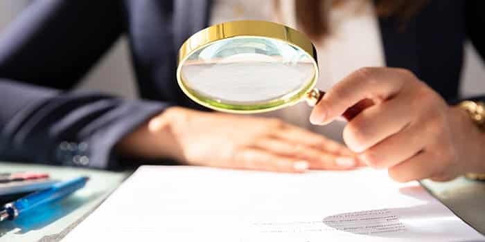 Woman examines documents under a magnifying glass