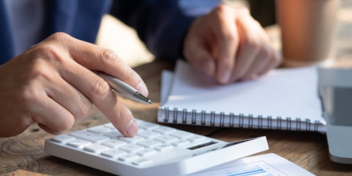 A man holding a pen and notepad, using calculator