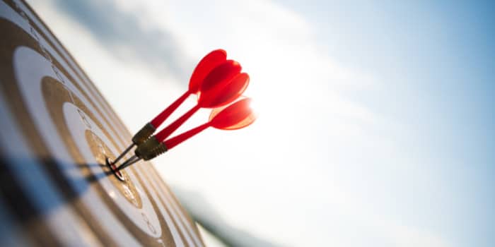 Three red darts shot at the center of a target representing an achievement