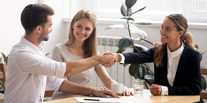 A businessman shakes hands with two businesswomen