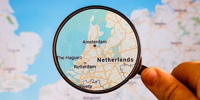 A person uses a magnifying glass to take a look at the map of the Netherlands