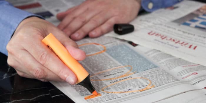 Man underlining job advertisements in a newspaper