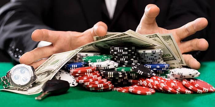 A poker player with a pile of chips, dollar bills and valuable items