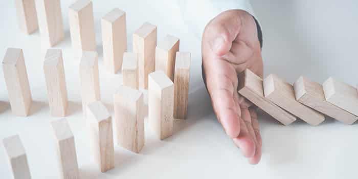 A man manages risk by stopping a row of tiles from falling