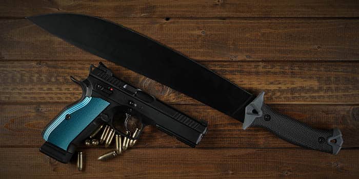 A gun and a machete on a wooden table