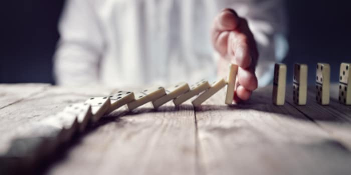 The hand of a man stopping falling dominoes