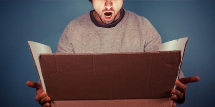 A surprised young man holding an opened box