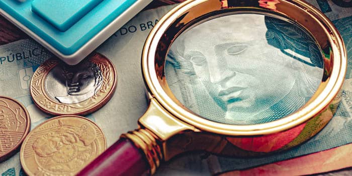 A magnifying glass over Brazilian Real banknotes