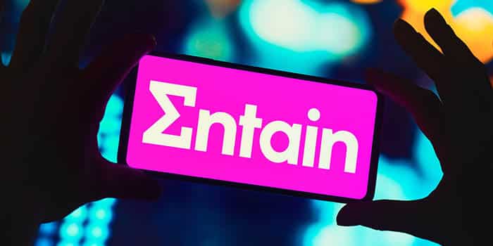 Person holds a mobile device with Entain's logo on it