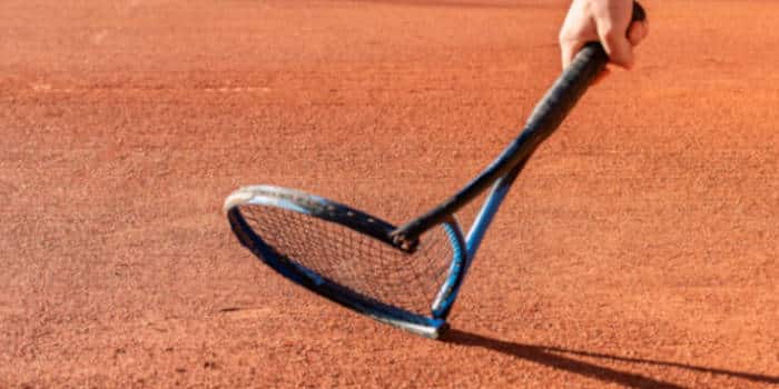 A man breaking a tennis racket in the ground