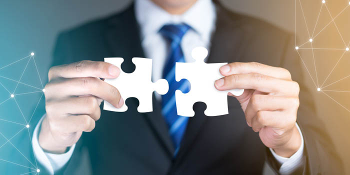 Businessman joins two pieces of puzzle as an allegory for M&A activity
