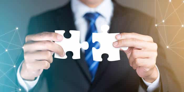 Businessman joins two pieces of puzzle as an allegory for M&A activity