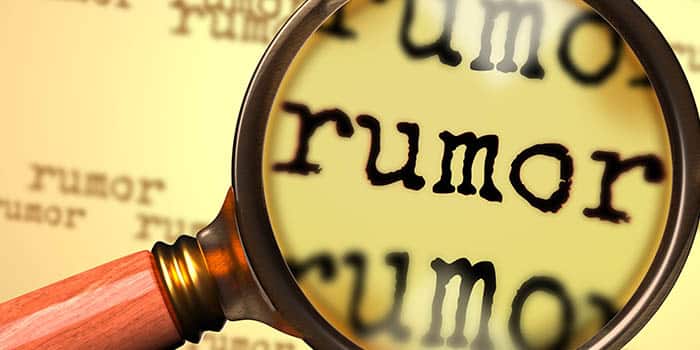 A magnifying glass zooms on the word rumor