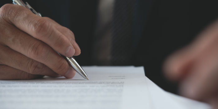 Close up photo of a man signing a document with a pen