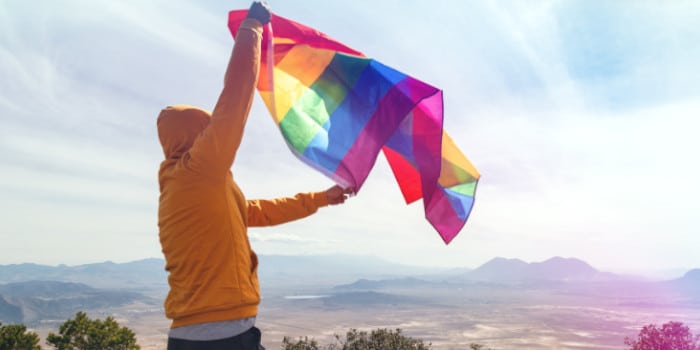 A person holding a LGBTQ+ flag