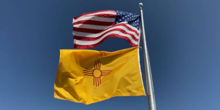 A US flag along with the flag of the state of New Mexico on a pole