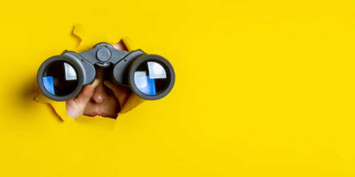 A woman holding binoculars, peeking at something.