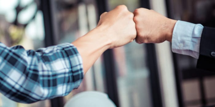 Close up photo of the hands of two members of a business team fist bumping