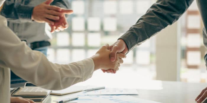 Two businessmen shake hands after a partnership, deal