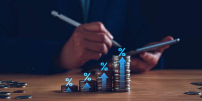 A concept for financial growth - businessman holding a tablet and coins stacked to show growth