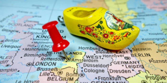 Pushpin placed on the Netherlands on the map of Europe along with a wooden miniature shoe
