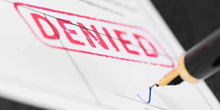 A person signs a document reading "denied"