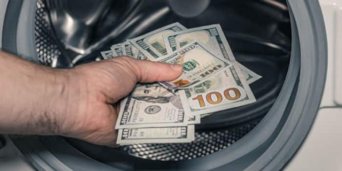 A person placing $100 bills into a washing machine