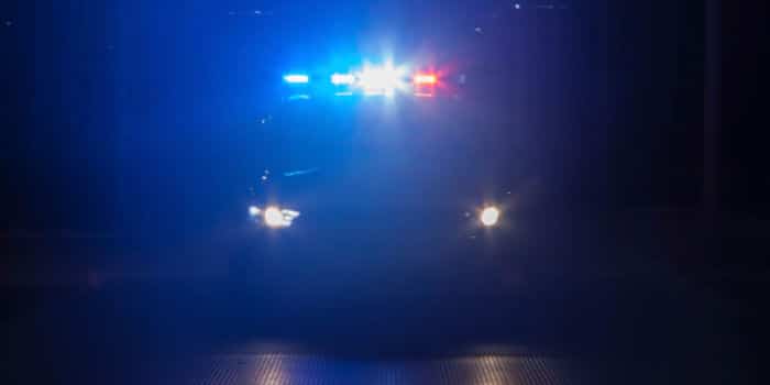 Police car with turned on emergency lights on a dark road