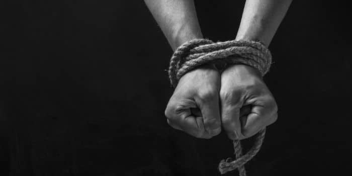 A close up of a person's hands tied with a rope